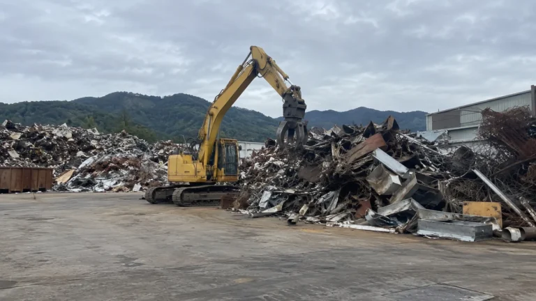 金属スクラップの山を重機で寄せている様子